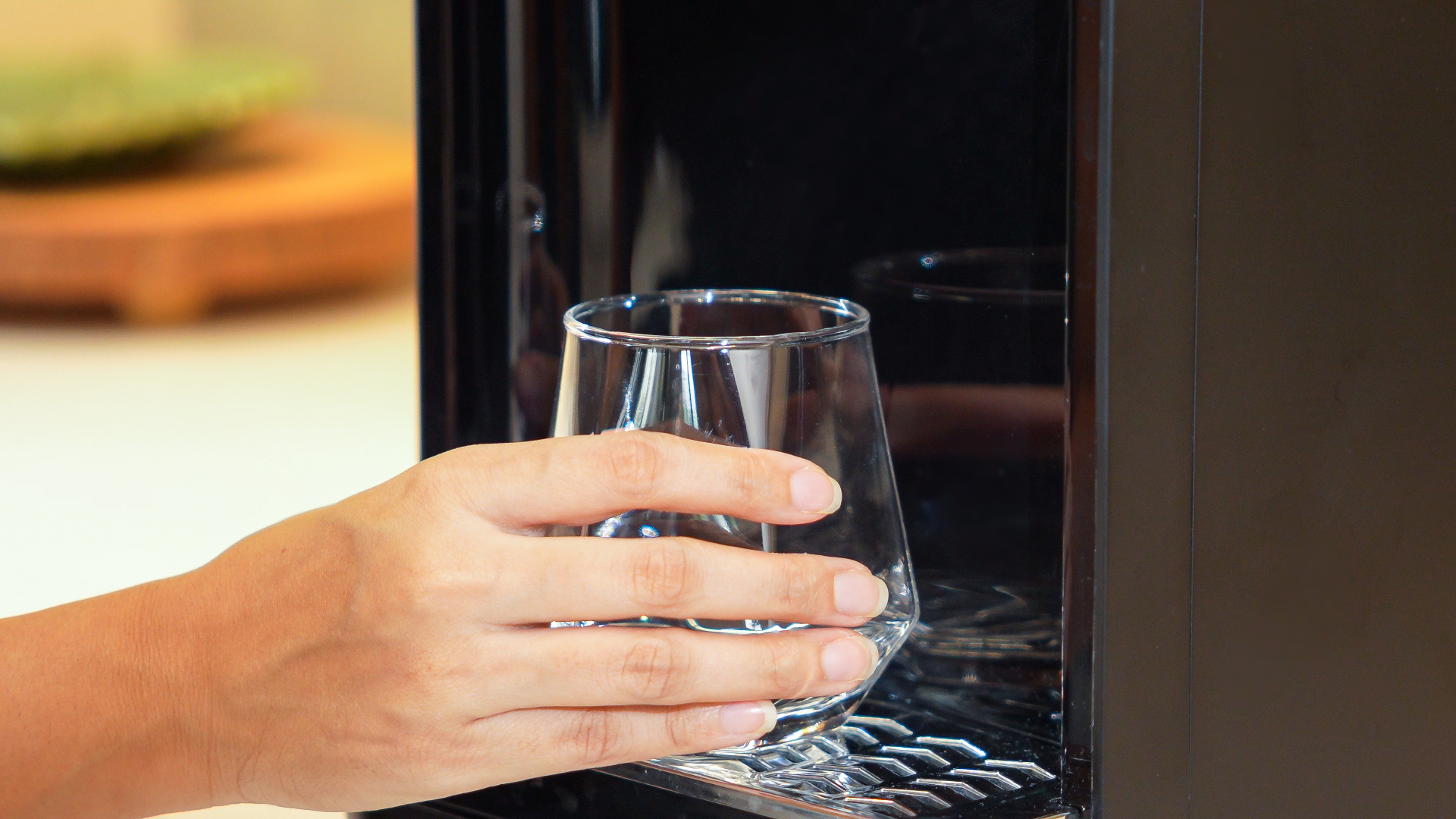 A hand holding a clear glass under the purifier